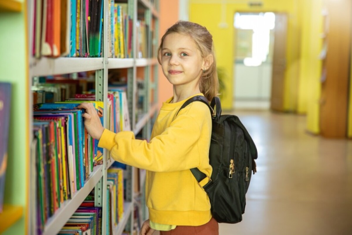 Fetita in biblioteca isi alege carti de citit