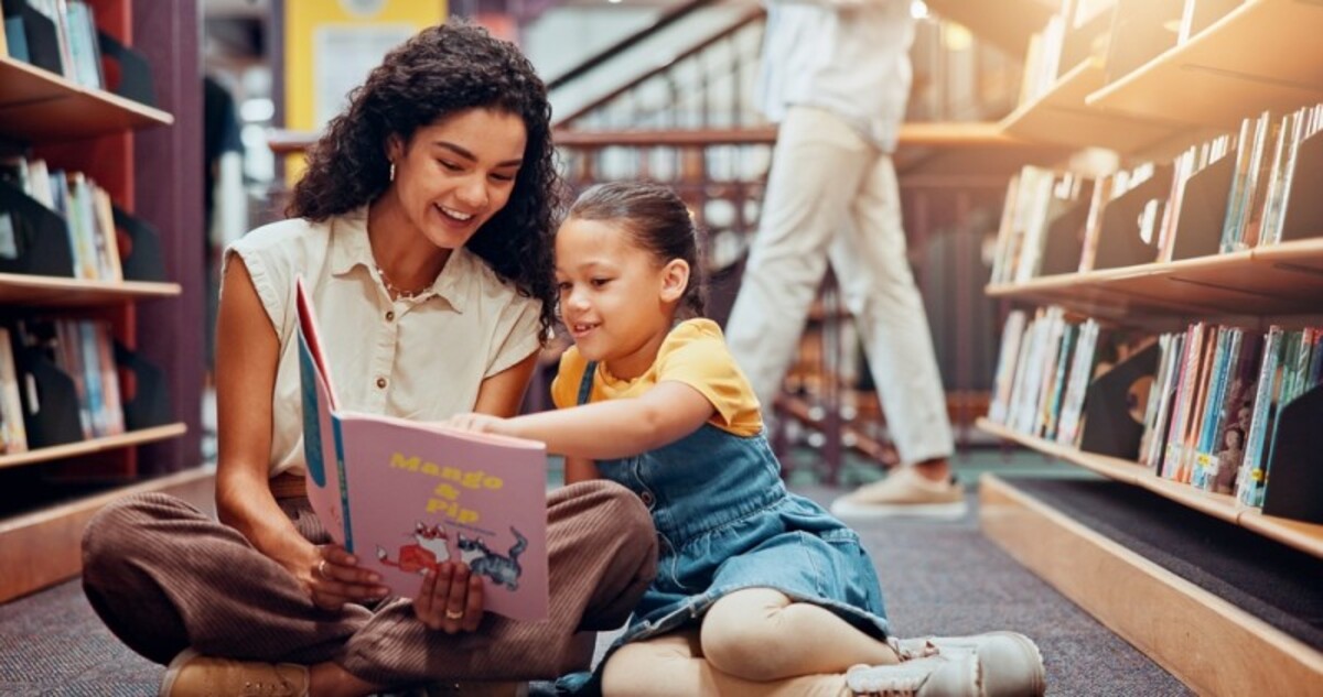 Mama ii citeste fetitei o carte pentru copii in biblioteca